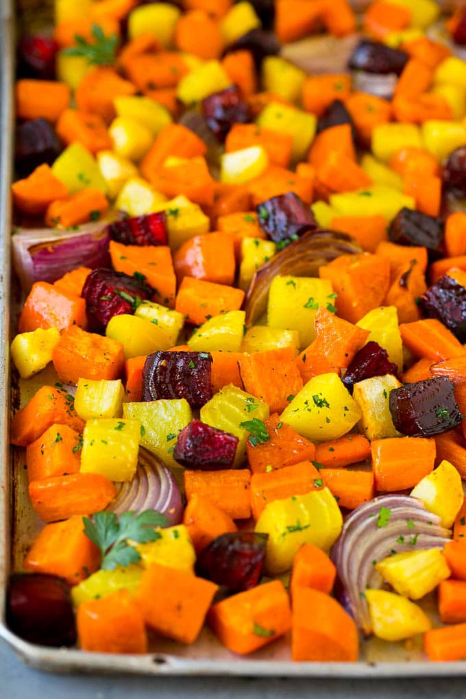 Roasted Root Vegetables Recipe | Roasted Sweet Potatoes | Roasted Beets | Roasted Carrots #carrots #beets #vegetables #sweetpotatoes #fall #parsnips #sidedish #uzhal #cleaneating #healthy Roasted root vegetables on a sheet pan, topped with chopped parsley.