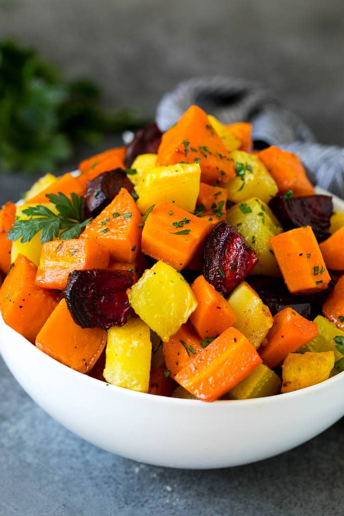 Roasted Root Vegetables Recipe | Roasted Sweet Potatoes | Roasted Beets | Roasted Carrots #carrots #beets #vegetables #sweetpotatoes #fall #parsnips #sidedish #uzhal #cleaneating #healthy A bowl of diced roasted root vegetables topped with parsley.