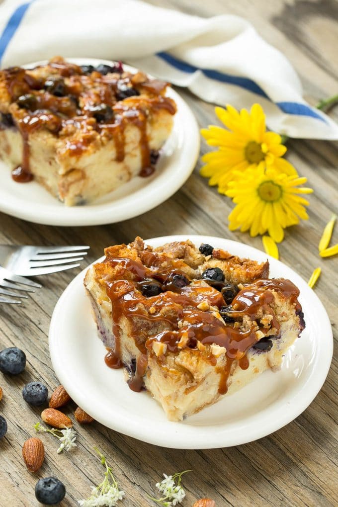 Blueberry Bread Pudding Recipe | Blueberry Bread Pudding | Easy Bread Pudding #blueberry #breadpudding #dessert #uzhal Two pieces of blueberry bread pudding on plates with salted caramel on top.