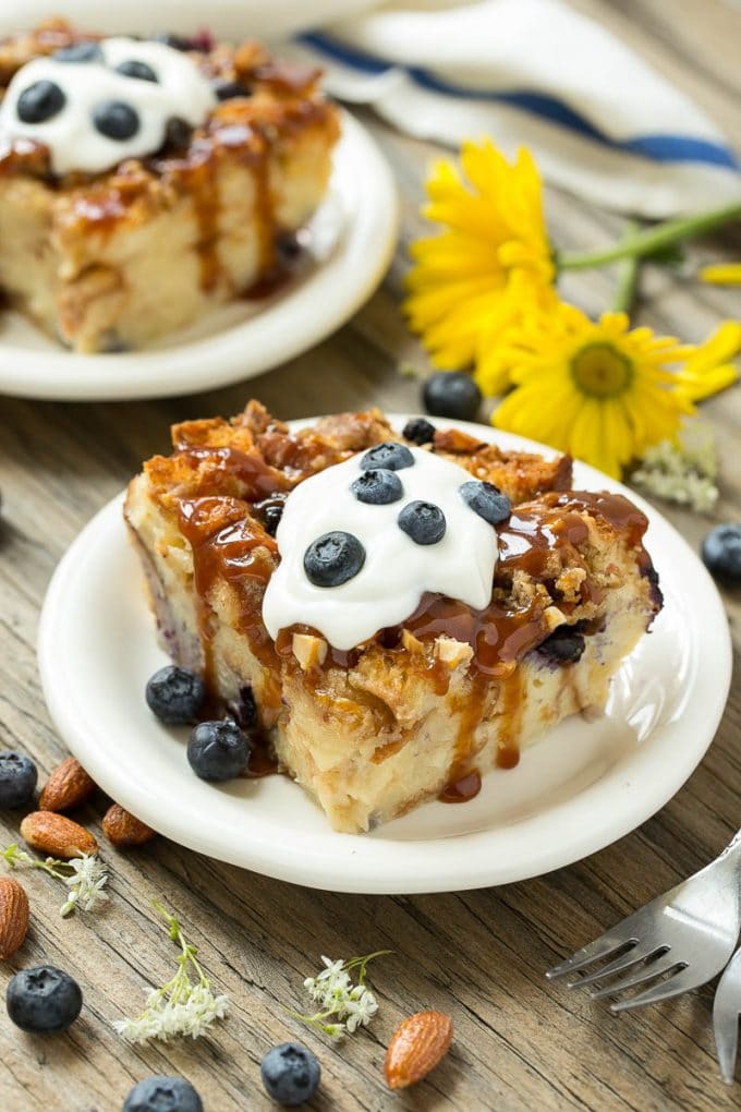 Blueberry Bread Pudding Recipe | Blueberry Bread Pudding | Easy Bread Pudding #blueberry #breadpudding #dessert #uzhal Slices of bread pudding on plates, topped with caramel and fresh berries.
