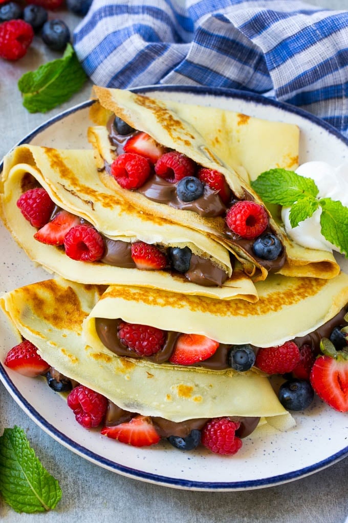 Nutella Crepes Recipe | Easy Crepes Recipe | Blender Crepes | Berry Crepes #crepes #nutella #nutellacrepes #blendercrepes #breakfast #uzhal A platter of crepes served with whipped cream.