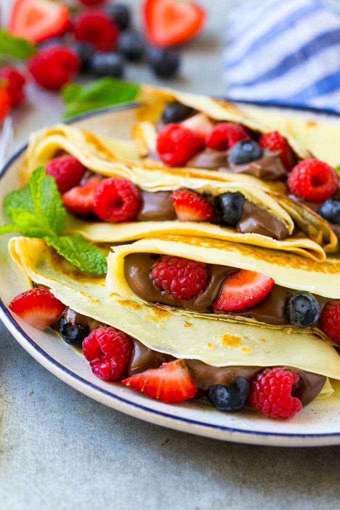 Nutella Crepes Recipe | Easy Crepes Recipe | Blender Crepes | Berry Crepes #crepes #nutella #nutellacrepes #blendercrepes #breakfast #uzhal A plate of Nutella crepes with strawberries, blueberries and raspberries.