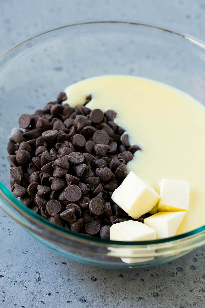 Chocolate Peanut Butter Fudge Recipe | Peanut Butter Cup Fudge | Easy Fudge Recipe #chocolate #peanutbutter #fudge #baking #dessert #uzhal Chocolate chips, condensed milk and butter in a mixing bowl.