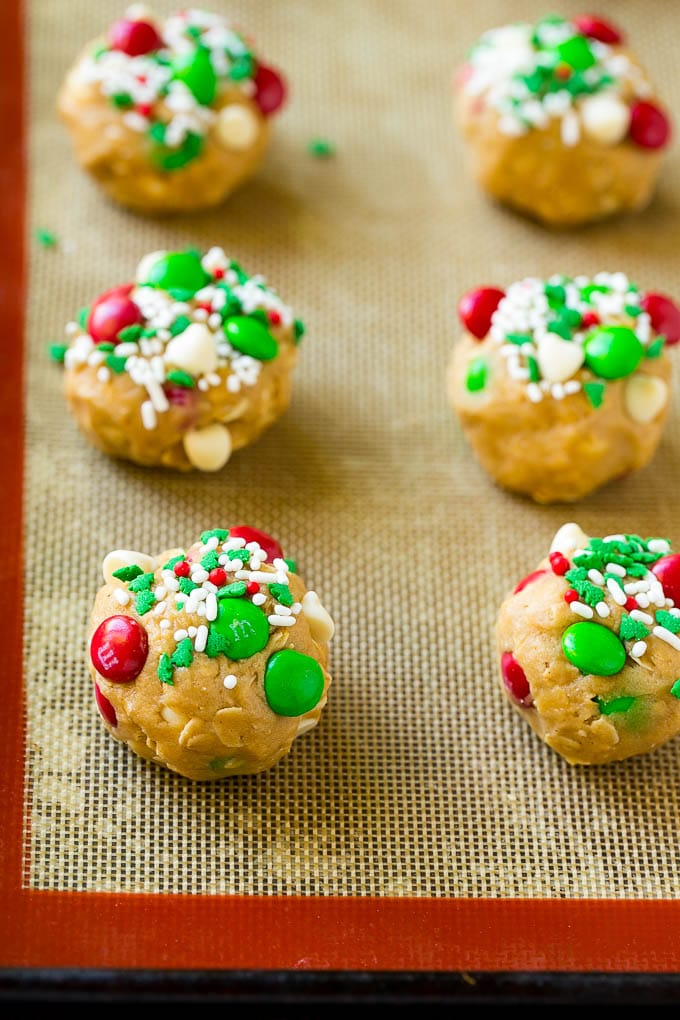 Christmas Monster Cookies Recipe | Oatmeal Cookies | Peanut Butter Cookies | M&M's Cookies #baking #cookies #dessert #peanutbutter #chocolate #uzhal #christmas #sprinkles Balls of cookie dough on a baking sheet.