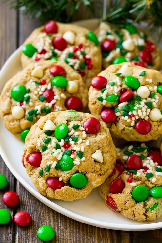 Christmas Monster Cookies Recipe | Oatmeal Cookies | Peanut Butter Cookies | M&M's Cookies #baking #cookies #dessert #peanutbutter #chocolate #uzhal #christmas #sprinkles A plate of Christmas monster cookies which are decorated with M&M's, white chocolate and sprinkles.