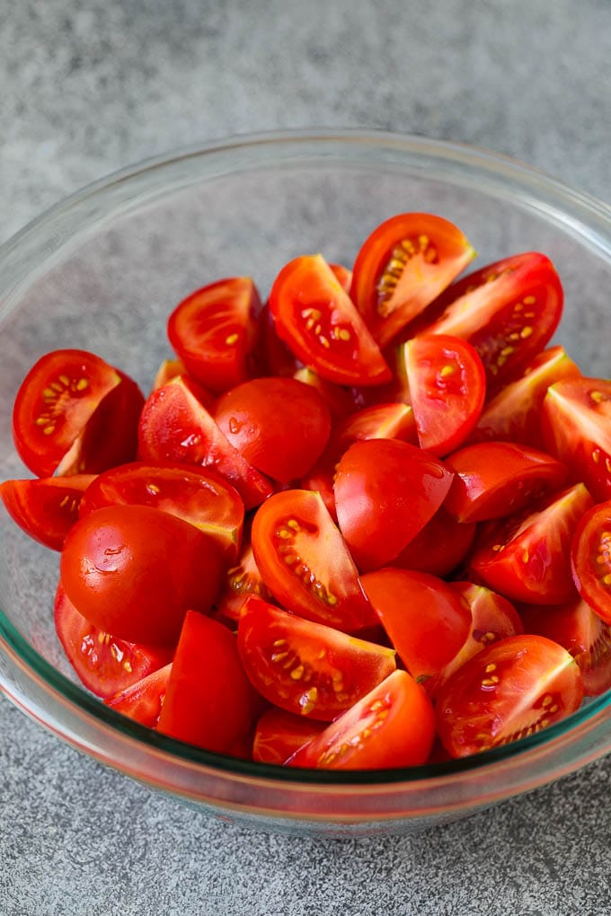 Caprese Salad Recipe | Tomato Salad #salad #tomato #mozzarella #cheese #basil #caprese #summer #uzhal Quartered tomatoes in a bowl.