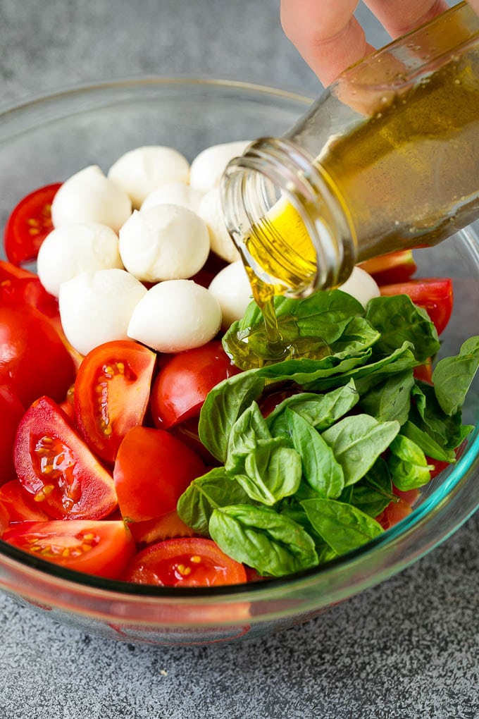 Caprese Salad Recipe | Tomato Salad #salad #tomato #mozzarella #cheese #basil #caprese #summer #uzhal Olive oil being poured over tomatoes, mozzarella and basil leaves.