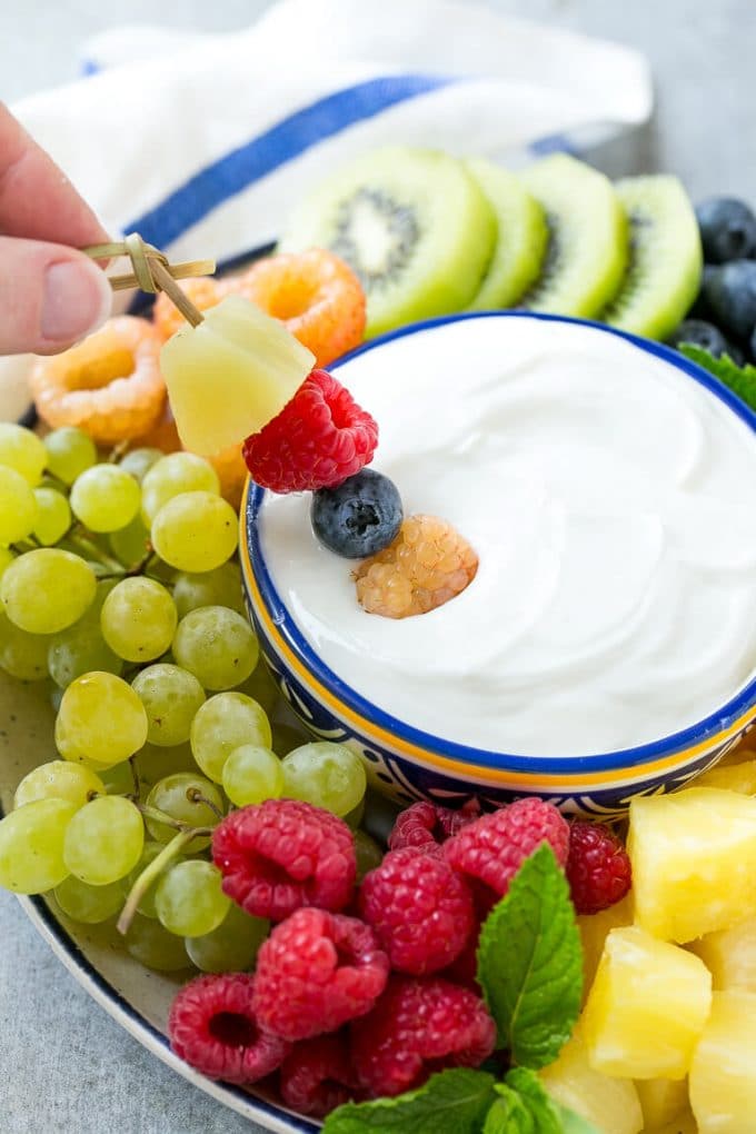 Cream Cheese Fruit Dip | Fruit Recipe | Fruit Dip #fruit #dip #creamcheese #snack #dessert #uzhal A skewer of berries going into a bowl of fruit dip.