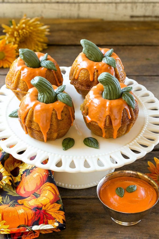 Pumpkin Spice Cake Recipe | Pumpkin Cake | Easy Pumpkin Cake | Thanksgiving Dessert #thanksgiving #pumpkin #cake #pumpkincake #spicecake #dessert #uzhal #holiday Pumpkin spice cake topped with orange glaze and fondant decorations on a serving platter.