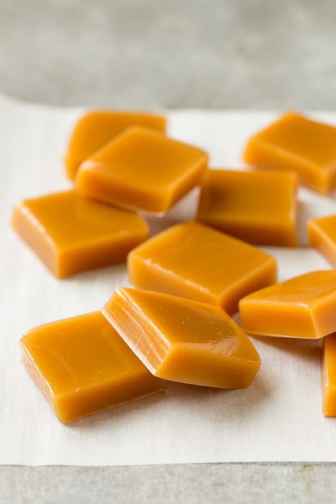 Microwave Caramels with Sea Salt Recipe | Homemade Caramels | Sea Salt Caramel | Homemade Candy #candy #caramels #caramel #microwavecaramels #homemade #dessert #uzhal Squares of cooked caramel on parchment.