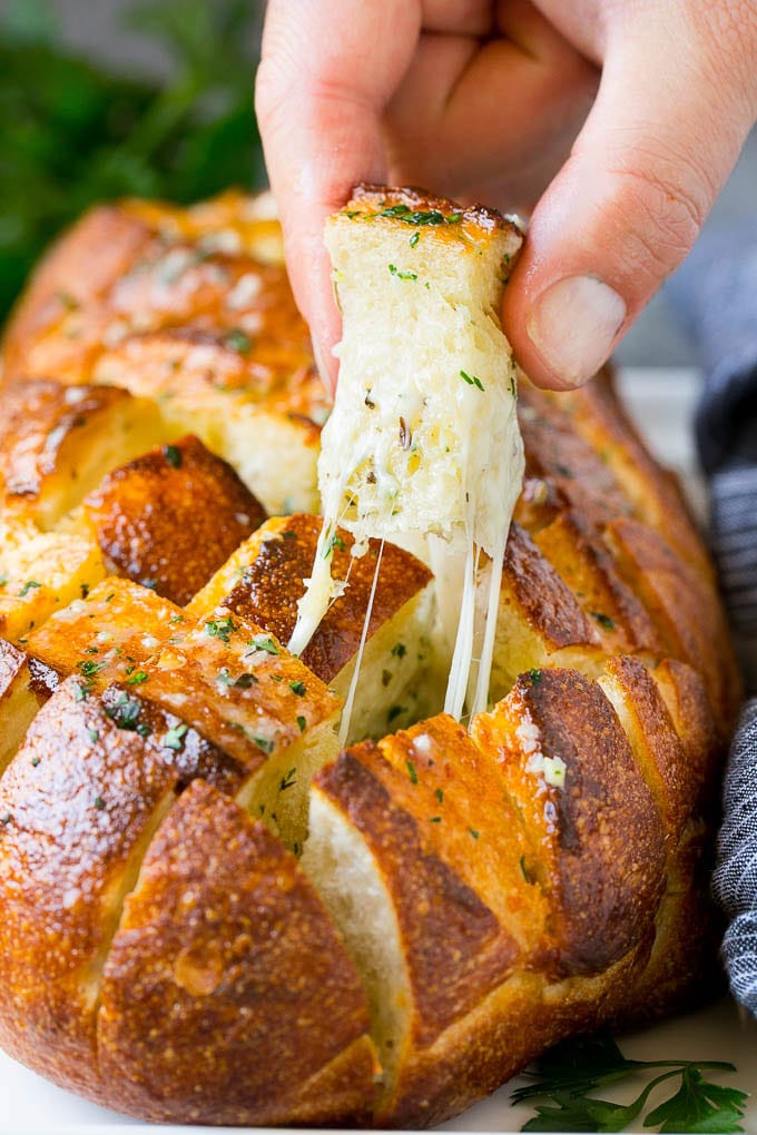 Pull Apart Bread | Garlic Bread | Cheese Bread #bread #garlic #cheese #sidedish #appetizer #uzhal A hand grabbing a piece of pull apart bread.