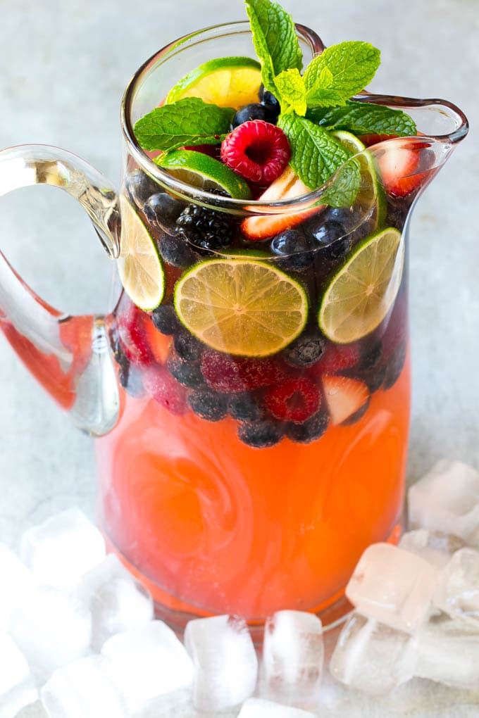 Berry Champagne Punch Recipe | Champagne Cocktail | Lime Cocktail | Berry Punch | Champagne Recipe #champagne #punch #berries #drink #uzhal A pitcher of a cocktail garnished with fruit and mint.