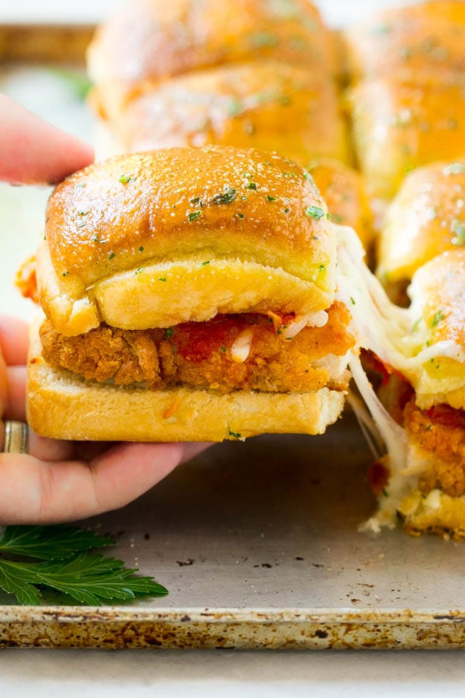 Chicken Parmesan Sliders | Chicken Parmesan Sandwich Recipe | Slider Sandwich Recipe #sliders #chickenparm #chickenparmesan #chickenparmesansliders #dinner #appetizer #uzhal A crispy chicken parmesan slider being pulled away by a hand.