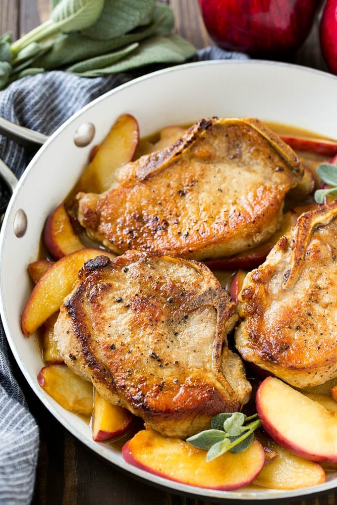 Apple Pork Chops Recipe | Pork Chops with Apples | Cider Pork Chops | Bone In Pork Chops Recipe #pork #porkchops #fall #apple #dinner #uzhal A pan of apple pork chops garnished with fresh sage.
