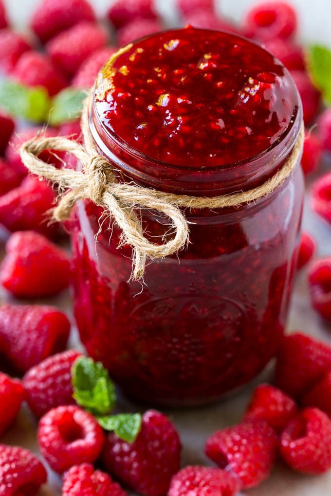 Raspberry Sauce Recipe | Homemade Raspberry Sauce | Raspberry Recipe #raspberries #dessert #uzhal A jar of homemade raspberry sauce surrounded by fresh raspberries.