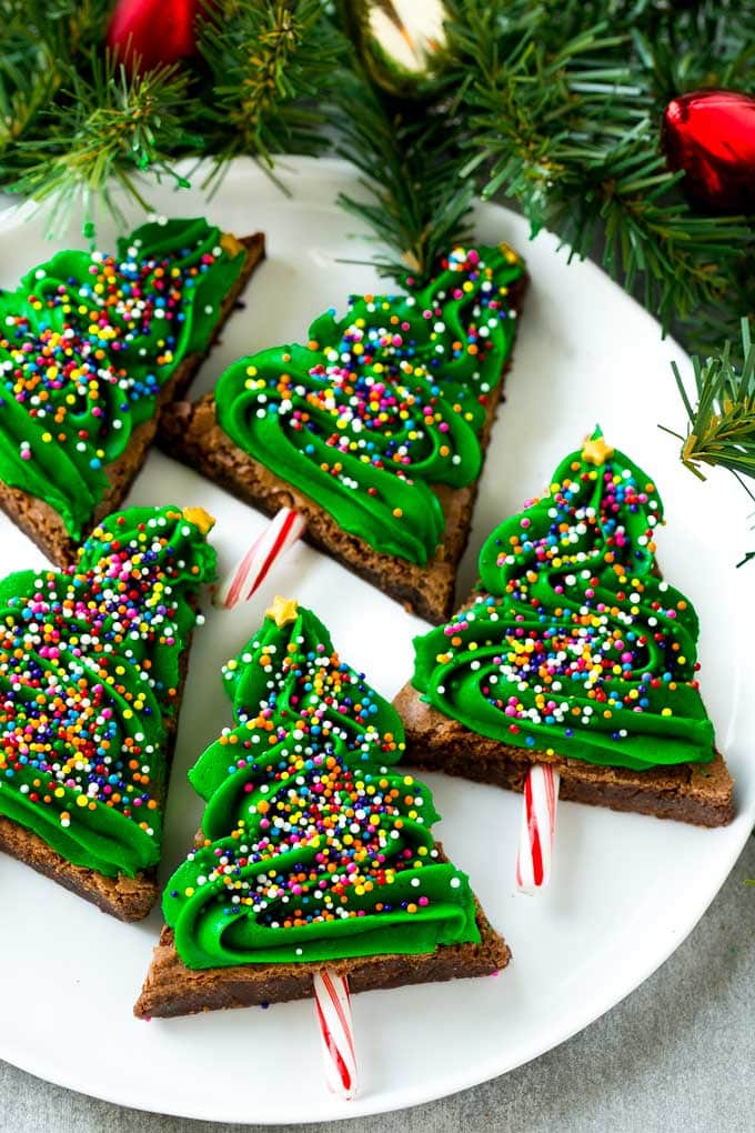 title="Christmas Tree Brownies | Christmas Brownies | Holiday Brownies | Christmas Tree Dessert #brownies #dessert #christmas #holiday #dessert #uzhal" Christmas Brownies topped with frosting and rainbow sprinkles on a plate.