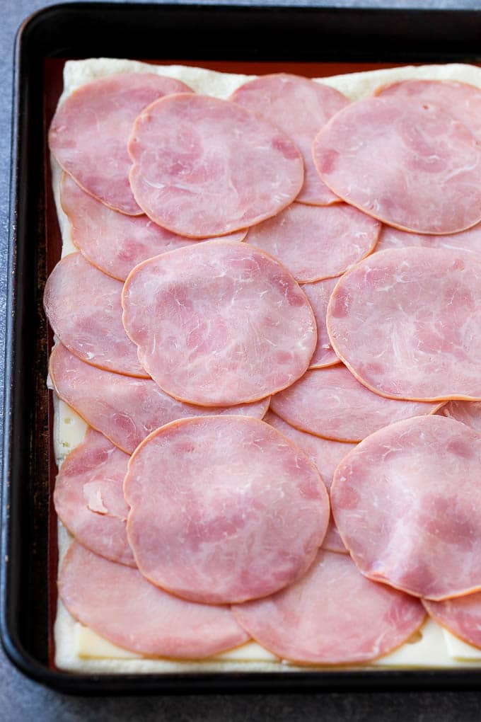 Ham and Cheese Pinwheels Recipe | Ham and Cheese Roll Ups | Ham and Cheese Rolls | Ham and Cheese Bread Rolls #ham #cheese #appetizer #pinwheels #uzhal Slices of ham and cheese on top of dough.