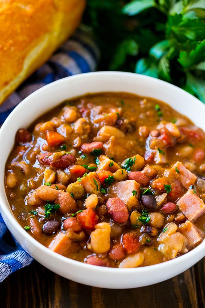 Slow Cooker Ham Bone Soup | Ham and Bean Soup | Ham Bone and Bean Soup | Ham Soup | Leftover Ham Recipe #ham #hamsoup #leftoverham #soup #slowcooker #crockpot #uzhal Crock pot ham bone soup in a bowl topped with parsley.
