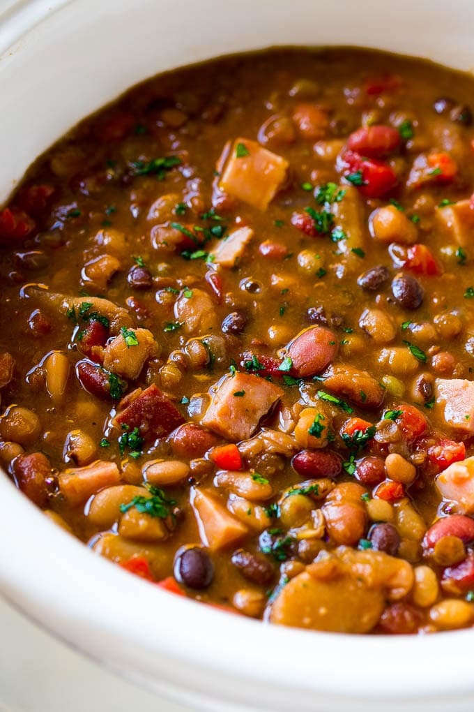 Slow Cooker Ham Bone Soup | Ham and Bean Soup | Ham Bone and Bean Soup | Ham Soup | Leftover Ham Recipe #ham #hamsoup #leftoverham #soup #slowcooker #crockpot #uzhal A slow cooker full of soup with parsley on top.