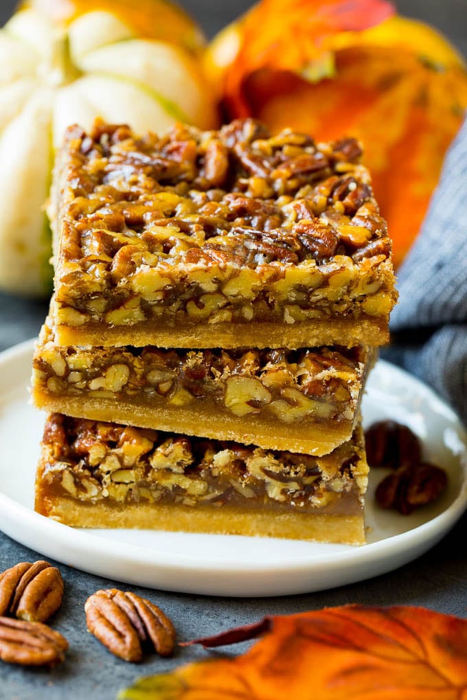 Pecan Pie Bars Recipe #pecans #pie #fall #pecanpie #dessert #thanksgiving #uzhal A stack of pecan pie bars on a plate.