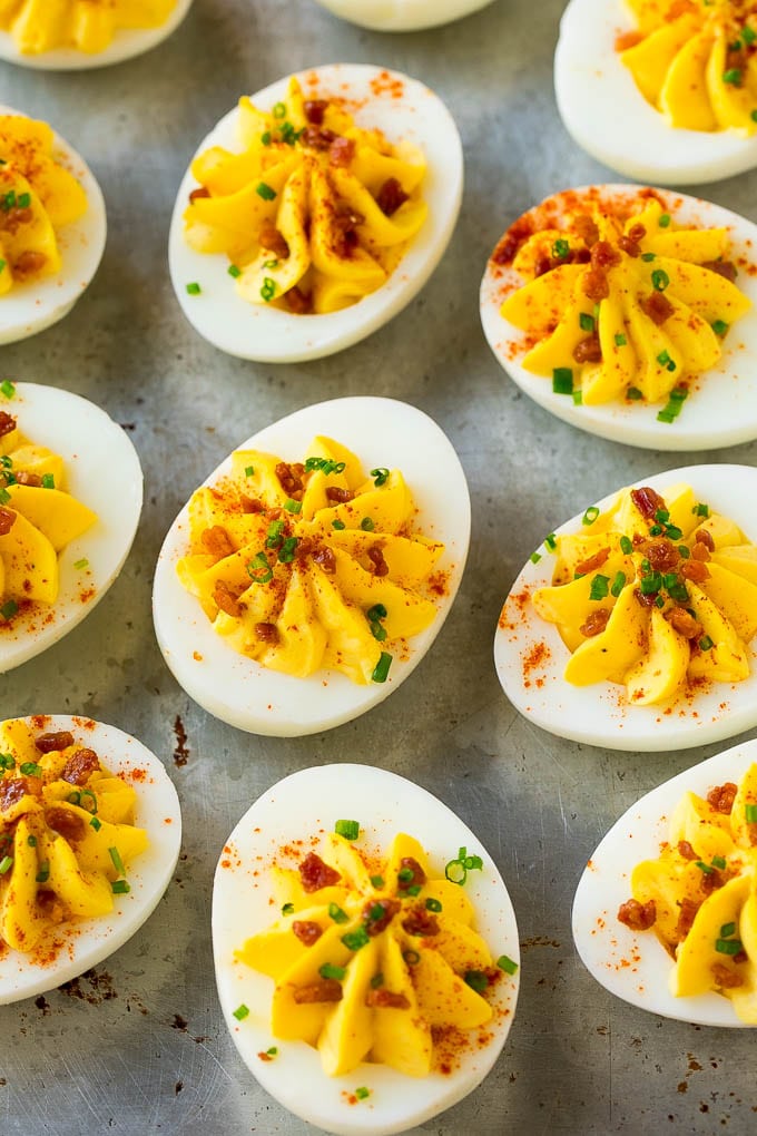 Bacon Deviled Eggs | Deviled Eggs Recipe #eggs #keto #lowcarb #bacon #appetizer #uzhal Bacon deviled eggs topped with chives and paprika on a sheet pan.