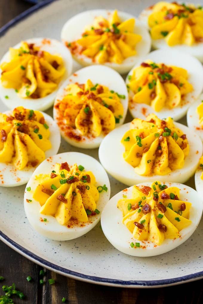 Bacon Deviled Eggs | Deviled Eggs Recipe #eggs #keto #lowcarb #bacon #appetizer #uzhal A plate of bacon deviled eggs garnished with sliced chives and smoked paprika.
