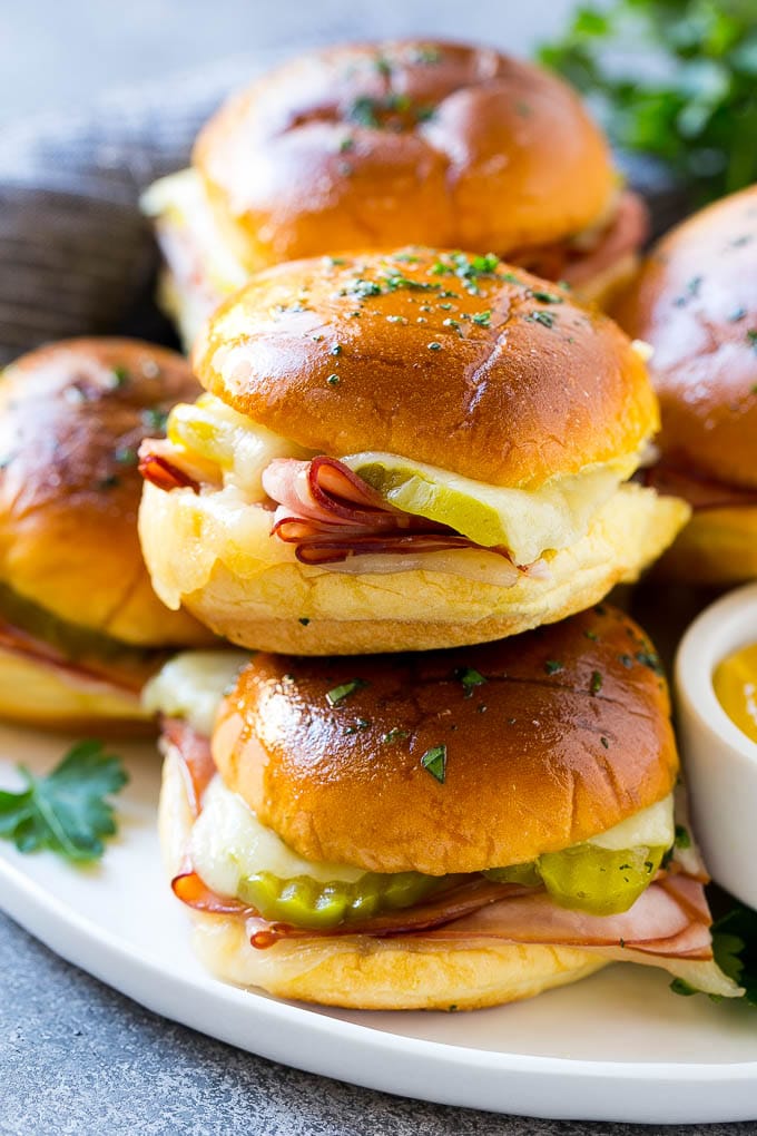 Cuban Sliders Recipe | Cuban Sandwich Recipe | Slider Sandwiches | Ham and Cheese Sliders #sliders #sandwiches #ham #cheese #appetizer #uzhal A pile of cuban sliders filled with ham, cheese and pickles.