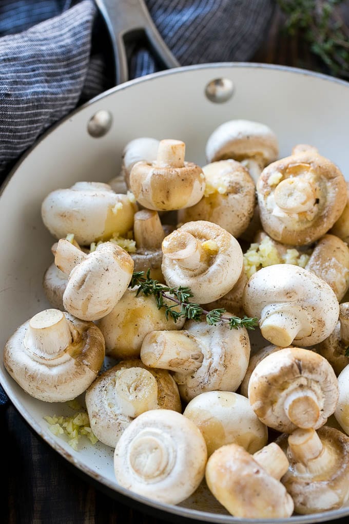 Garlic Mushrooms Recipe | Steakhouse Mushrooms | Sauteed Mushrooms | Garlic Butter Mushrooms | Mushroom Side Dish #mushrooms #butter #keto #lowcarb #dinner #sidedish #uzhal Uncooked buttons with herbs and butter in a frying pan.