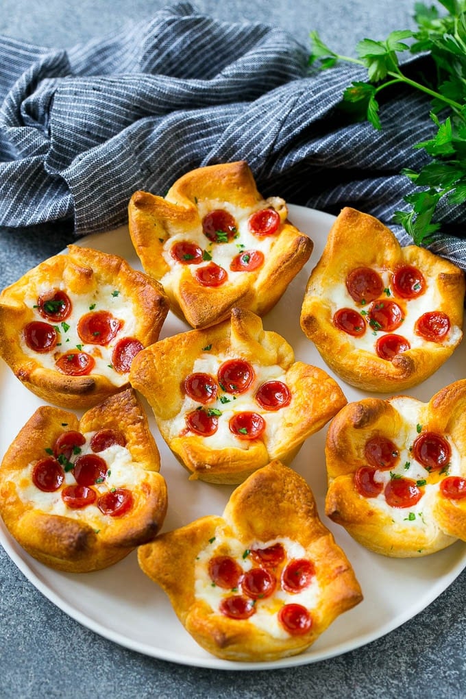Pizza Muffins Recipe | Pizza Bites | Pizza Cups | Pizza Appetizer #pizza #appetizer #uzhal Pizza muffins on a serving plate garnished with parsley.