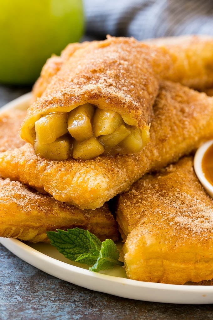 Fried Apple Pies Recipe | McDonald's Copycat Recipe | Apple Pie | Apple Hand Pies #pie #apples #applepie #dessert #snack #uzhal Fried apple pies on a plate served with caramel sauce and topped with cinnamon sugar.