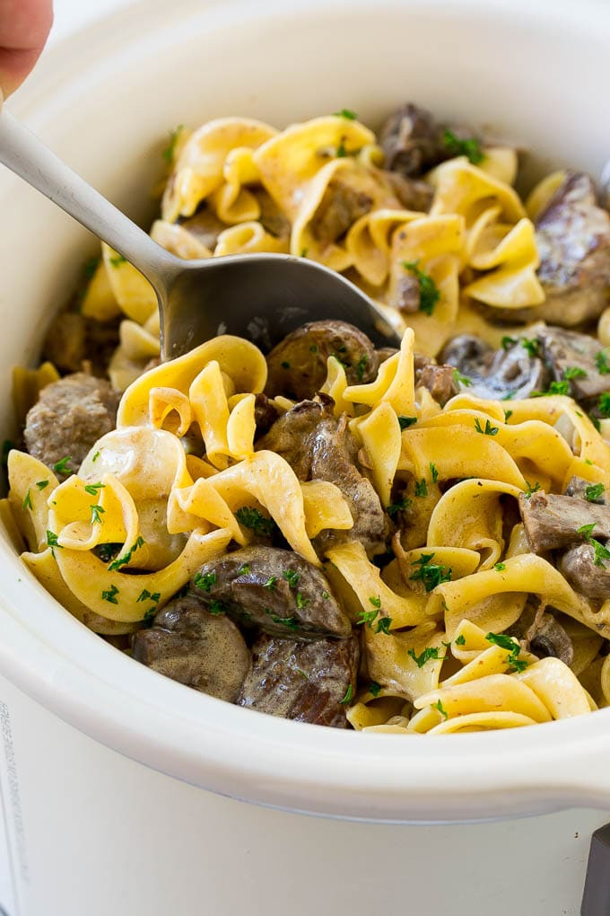 Slow Cooker Beef Stroganoff Recipe | Crock Pot Beef Stroganoff | Beef Recipe #slowcooker #crockpot #beef #mushrooms #pasta #dinner #uzhal A crock pot of beef stroganoff with a serving spoon in it.