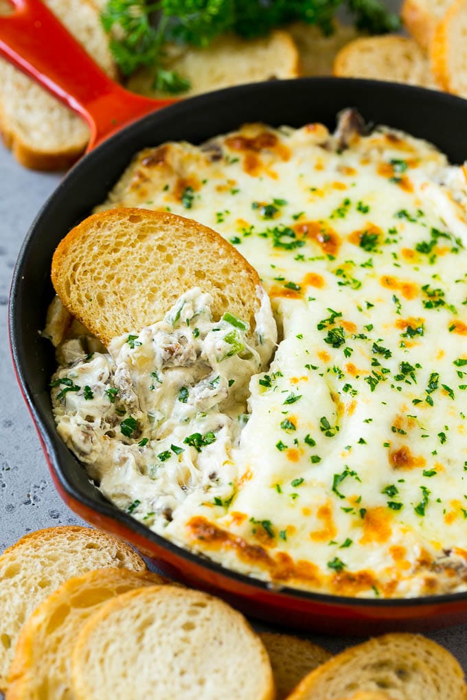 Philly Cheesesteak Dip Recipe | Cheesy Dip | Baked Cheese Dip #steak #dip #appetizer #cheese #uzhal Philly cheesesteak dip with a baguette piece scooping some dip out.