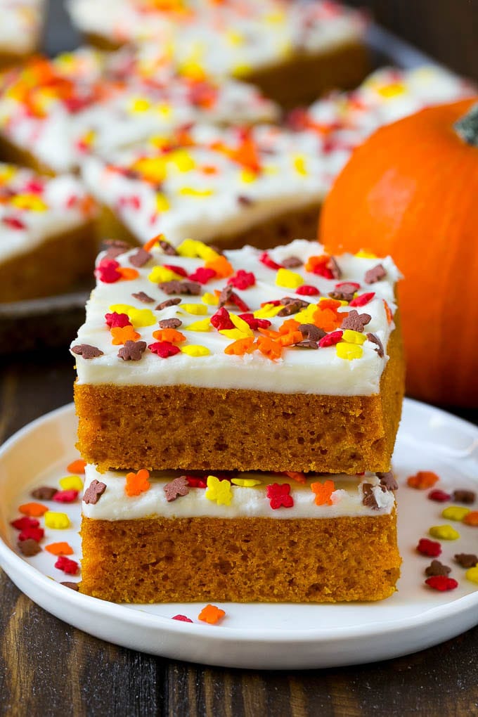 Pumpkin Bars Recipe | Pumpkin Cake | Pumpkin Dessert #pumpkin #fall #dessert #uzhal #thanksgiving A stack of pumpkin bars topped with frosting and sprinkles.