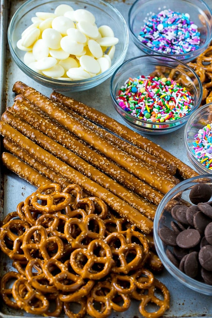 Chocolate Covered Pretzels Recipe | Sprinkle Pretzels | No Bake Dessert #pretzels #chocolate #christmas #sprinkles #candy #uzhal Ingredients including candy melts and sprinkles on a sheet pan.
