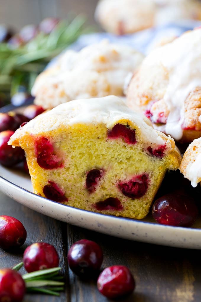Cranberry Muffins Recipe | Cranberry Orange Muffins #cranberry #muffins #orange #fall #dessert #uzhal A plate of muffins with one cut in half.
