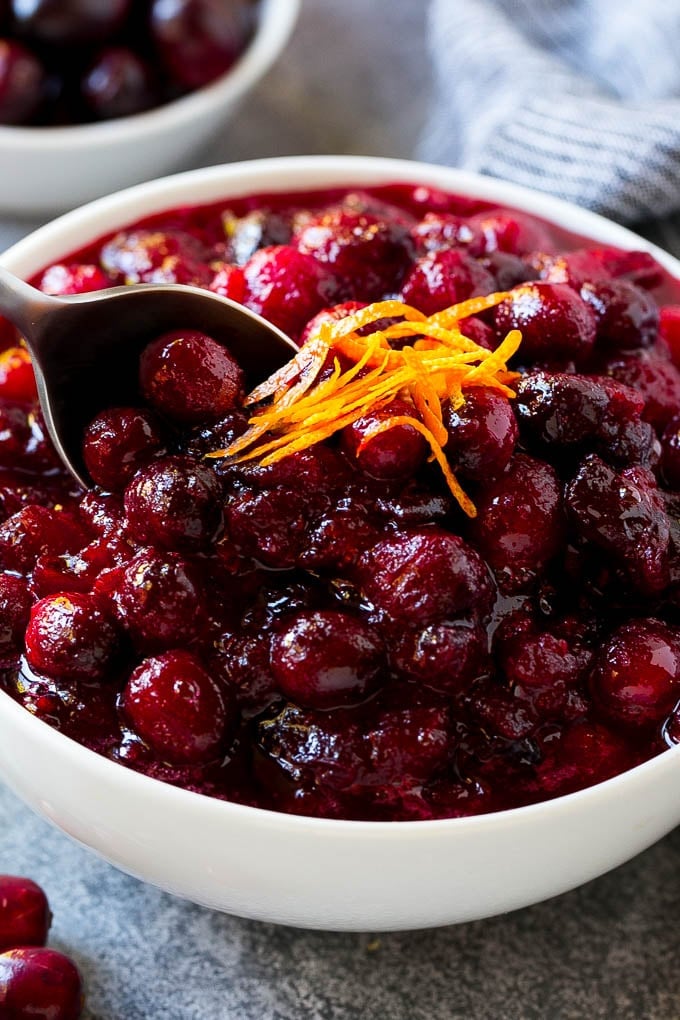 Cranberry Orange Sauce Recipe | Homemade Cranberry Sauce | Fresh Cranberry Sauce #cranberry #orange #fall #thanksgiving #sauce #dinner #uzhal A serving spoon in a bowl of cranberry orange sauce.