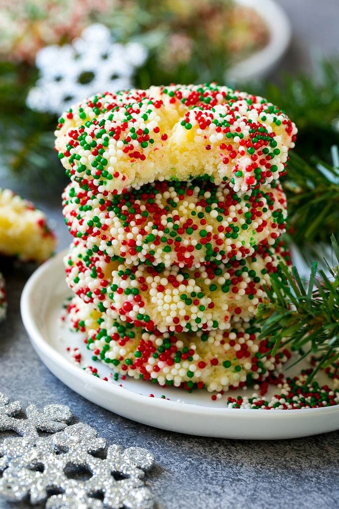 Gooey Butter Cookies Recipe | Cake Mix Cookies | Sprinkle Cookies | Christmas Cookies #cookies #butter #sprinkles #christmas #dessert #baking #uzhal A stack of gooey butter cookies with a bite taken out of one.