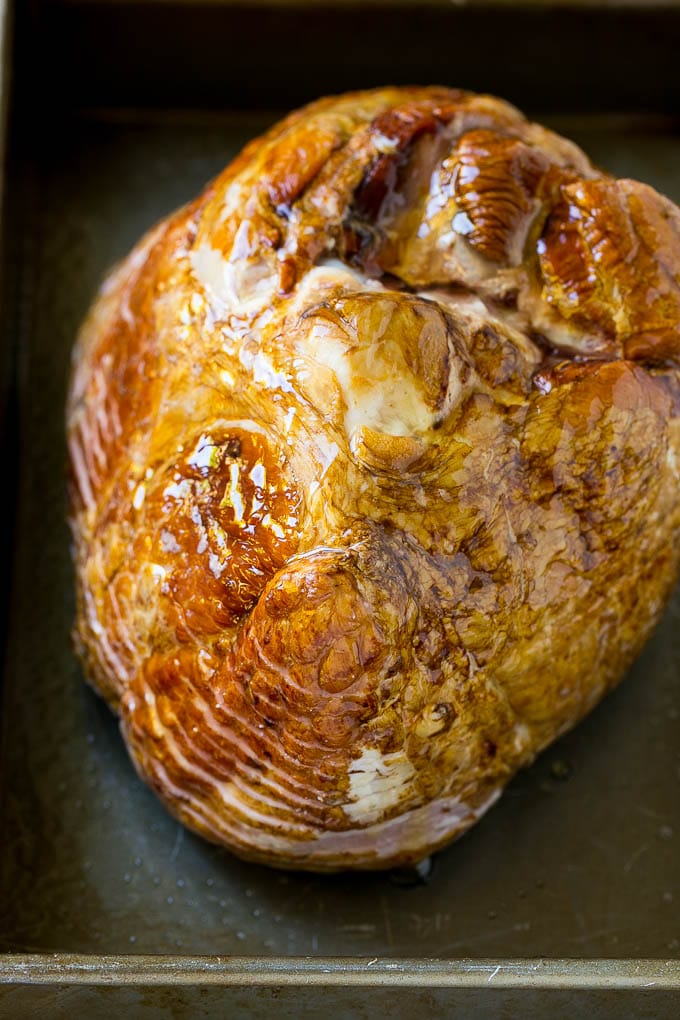 Honey Baked Ham Recipe | Glazed Ham | Holiday Ham #ham #dinner #uzhal #christmas #thanksgiving #easter A honey coated ham, face down, in a baking dish.