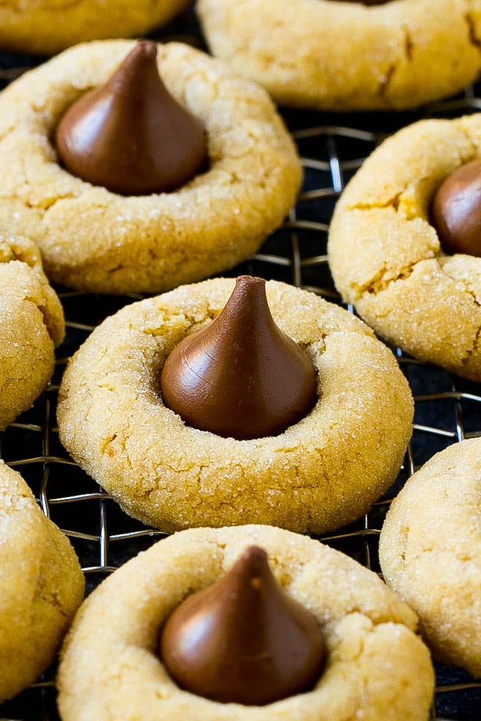 Peanut Butter Blossoms Recipe | Hershey Kiss Cookies | Chocolate Peanut Butter Cookies #cookies #peanutbutter #chocolate #dessert #baking #christmas #christmascookies #uzhal Peanut butter blossom cookies on a cooling rack.