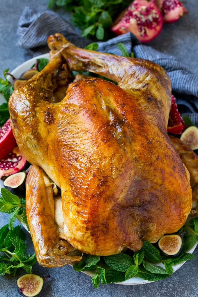 Roast Turkey Recipe | Thanksgiving Turkey | Holiday Turkey | Baked Turkey #turkey #thanksgiving #christmas #dinner #glutenfree #uzhal A Thanksgiving roast turkey on a serving platter garnished with herbs, pomegranate and figs.