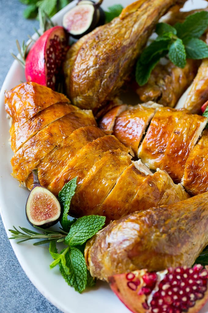 Roast Turkey Recipe | Thanksgiving Turkey | Holiday Turkey | Baked Turkey #turkey #thanksgiving #christmas #dinner #glutenfree #uzhal Sliced roast turkey on a serving platter with rosemary, pomegranate and figs.