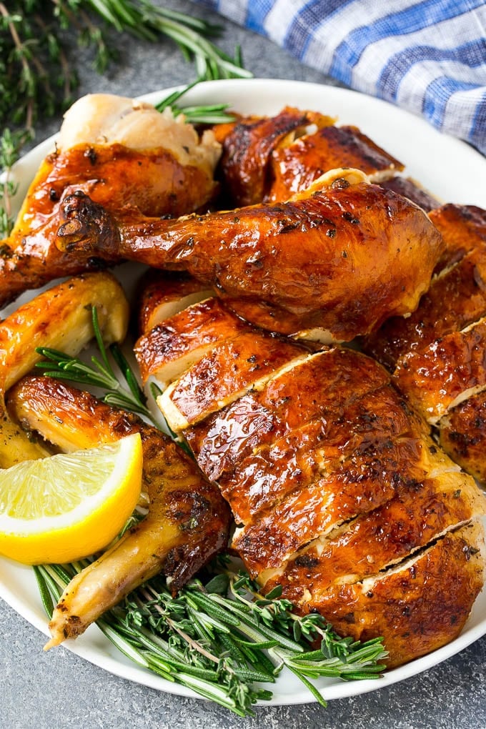 Carved roasted chicken on a serving platter with fresh herbs.