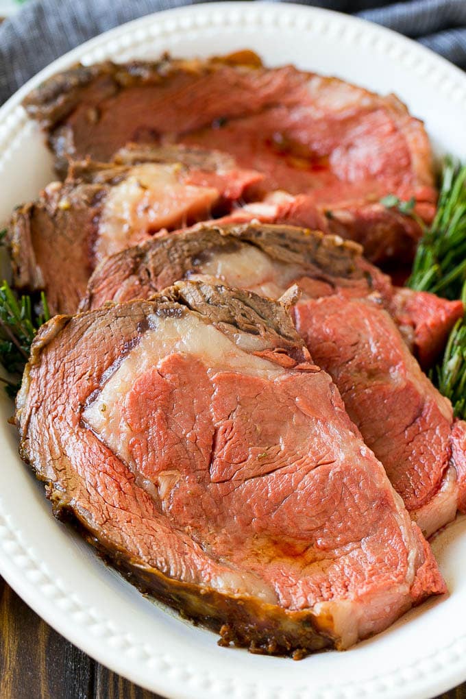Smoked Prime Rib Recipe | Easy Prime Rib | Smoked Beef | Holiday Prime Rib #primerib #beef #smoker #dinner #uzhal #christmas #thanksgiving #lowcarb #keto Slices of beef garnished with fresh herbs.