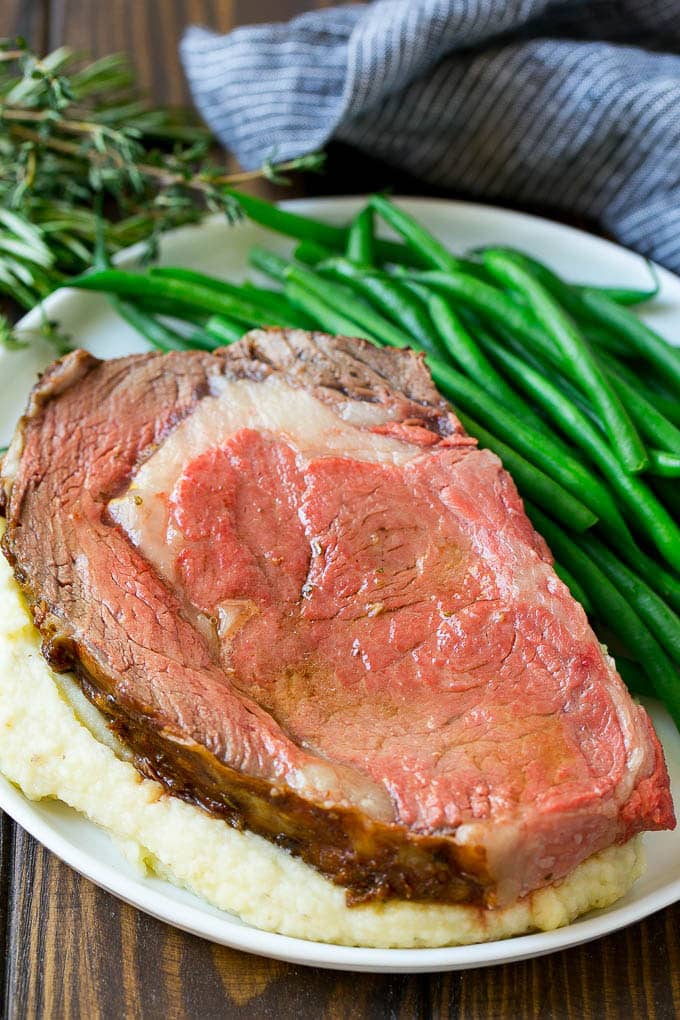 Smoked Prime Rib Recipe | Easy Prime Rib | Smoked Beef | Holiday Prime Rib #primerib #beef #smoker #dinner #uzhal #christmas #thanksgiving #lowcarb #keto A slice of prime rib over mashed potatoes with green beans on the side.
