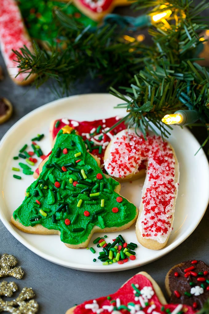 Christmas Sugar Cookies Recipe | Christmas Cookies #cookies #frosting #sprinkles #sugarcookies #christmas #dessert #uzhal A selection of Christmas sugar cookies served on a plate, with holiday decorations in the background.