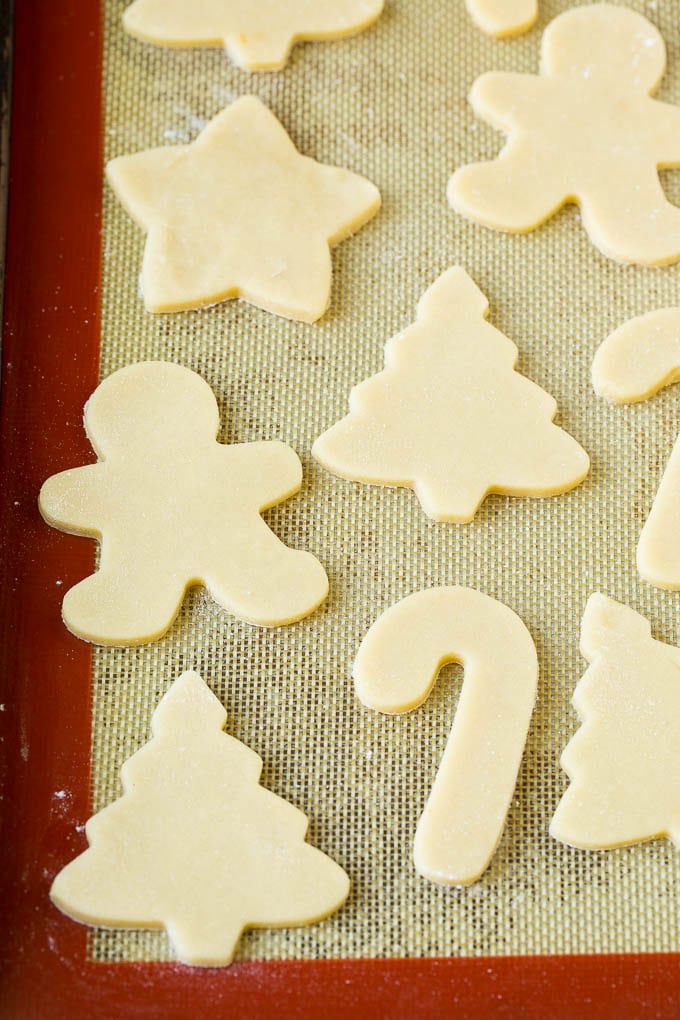 Christmas Sugar Cookies Recipe | Christmas Cookies #cookies #frosting #sprinkles #sugarcookies #christmas #dessert #uzhal Cookie dough cut into holiday shapes on a baking sheet.