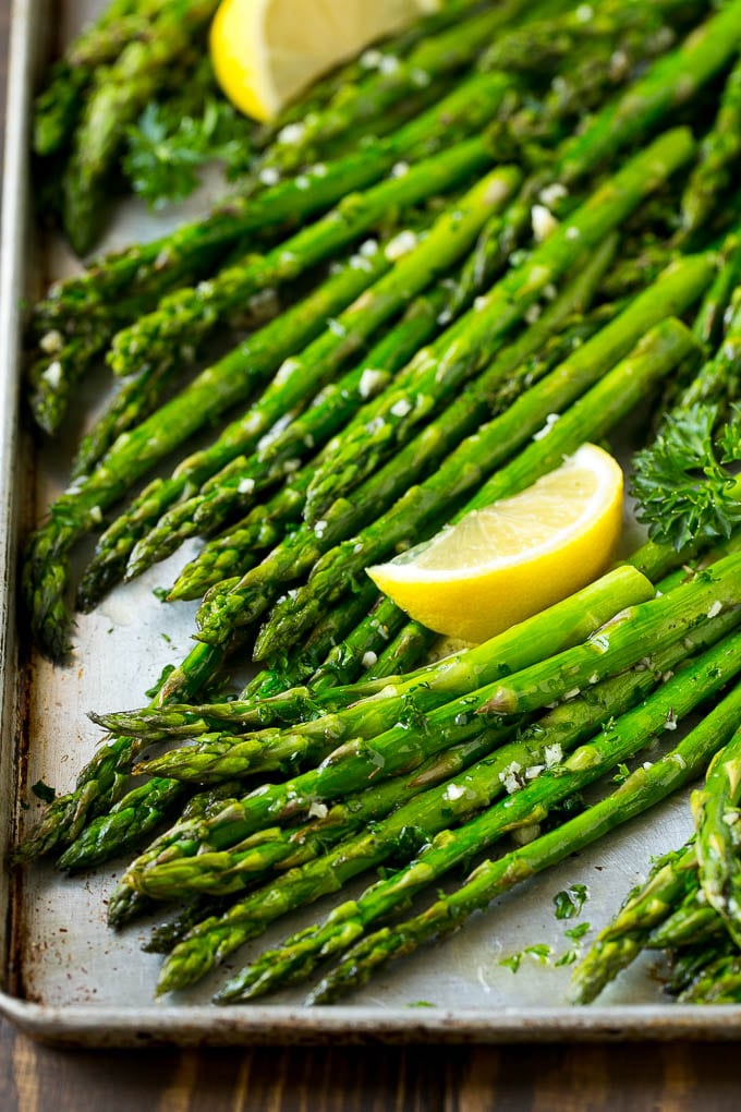 Roasted Asparagus Recipe | Baked Asparagus | Asparagus Side Dish #asparagus #garlic #sidedish #keto #lowcarb #dinner #uzhal Roasted asparagus on a sheet pan, topped with chopped parsley and garnished with lemon wedges.