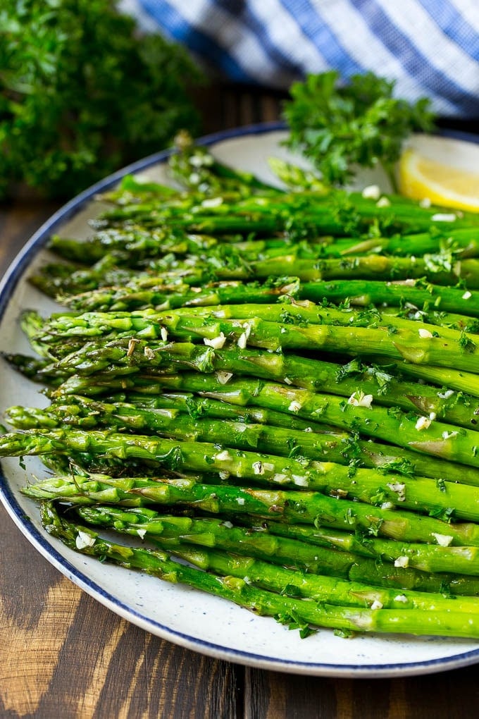 Roasted Asparagus Recipe | Baked Asparagus | Asparagus Side Dish #asparagus #garlic #sidedish #keto #lowcarb #dinner #uzhal A serving plate of roasted asparagus topped with chopped parsley.