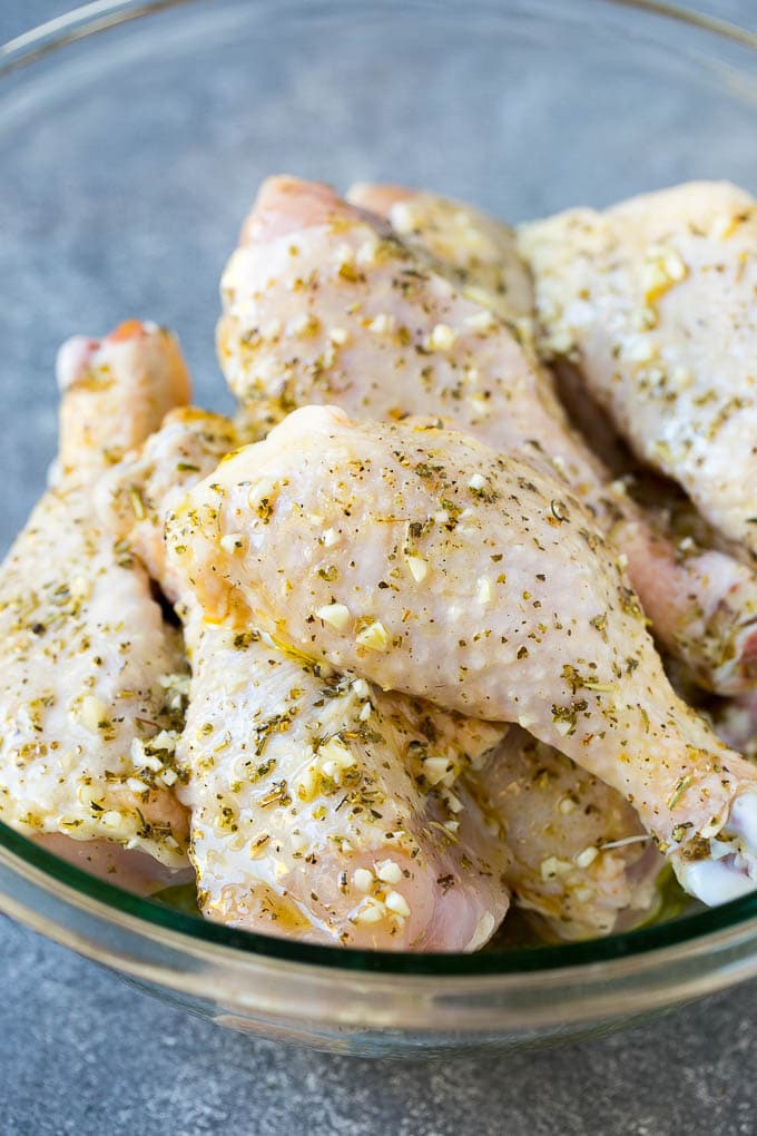 A bowl of chicken legs in a garlic and herb marinade.
