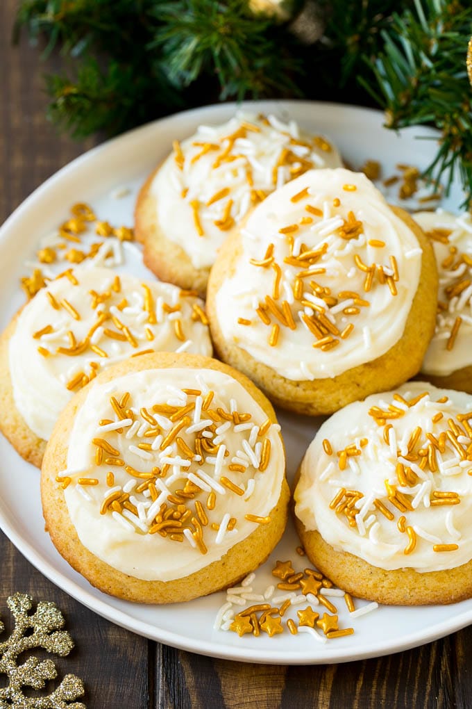 Eggnog Cookies Recipe | Holiday Cookies | Christmas Cookies #cookies #eggnog #baking #christmas #sprinkles #dessert #uzhal Eggnog cookies topped with frosting and gold sprinkles on a serving plate.